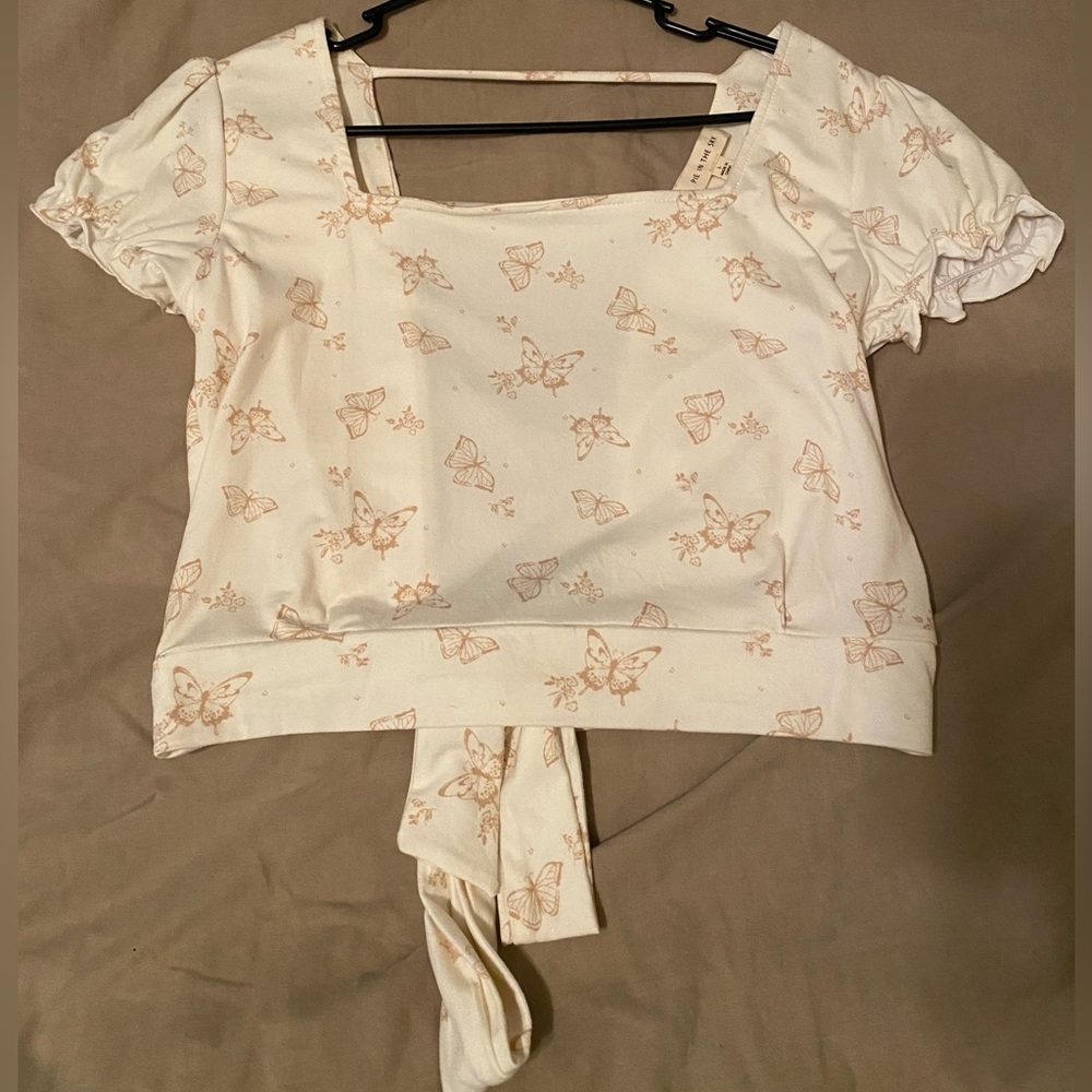 cream colored backless shirt with tan butterflies